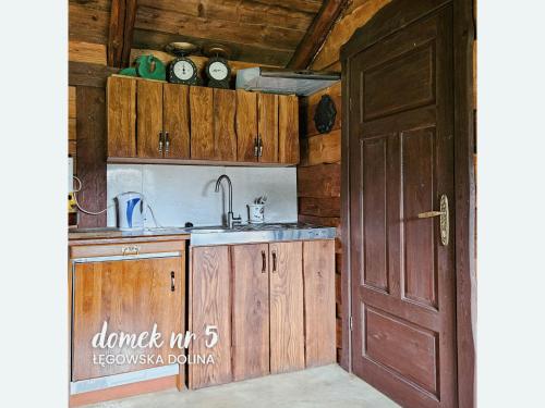 a kitchen with wooden cabinets and a sink and a door at Łęgowska Dolina in Olecko