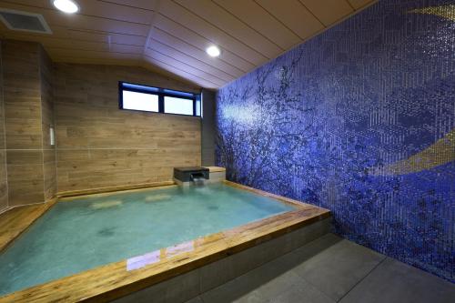 a hot tub in a bathroom with a blue wall at Almont Hotel Sendai in Sendai