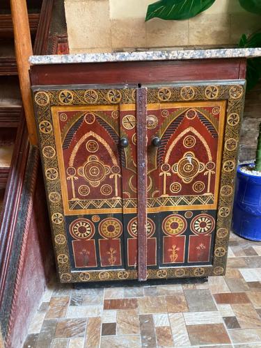 a wooden door with a design on it on a tile floor at RIAD Tamazouzt in Essaouira