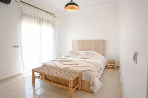 a white bedroom with a bed and a bench at 6-person appartment, terrace and spa in Marrakech