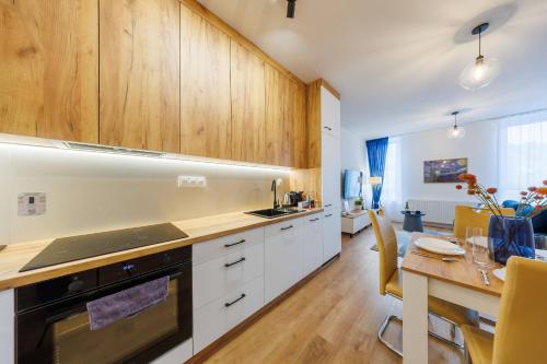 a kitchen with wooden cabinets and a dining table at Onyx Oasis Residence- City Centre, Free Parking by StayNest in Rzeszów