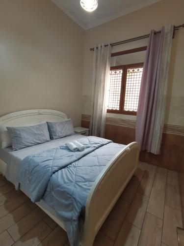 a bedroom with a bed with blue sheets and a window at Marhaba in Nador