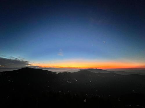 a view of the sunset from the top of a mountain at Sunny Horizon - The Valley View Penthouse in Murree