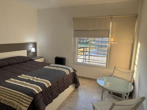Un dormitorio con una cama y una mesa y una ventana. en Departamento Castello -Viedma, en Viedma