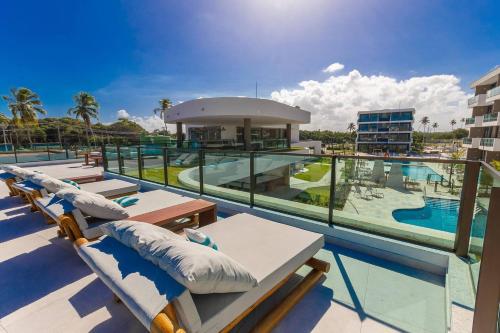 einen Resortbalkon mit Liegestühlen und einem Pool in der Unterkunft Flat Makia Beach Experience Muro Alto Porto de Galinhas in Porto De Galinhas