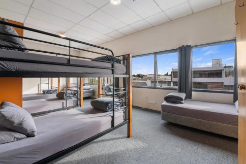 a group of bunk beds in a room with windows at Rock Solid Backpackers Rotorua in Rotorua