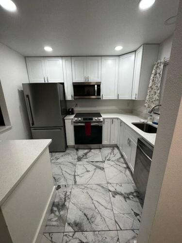 a kitchen with white cabinets and a marble floor at Duplex on CANAL all updated new furniture in Rotonda West