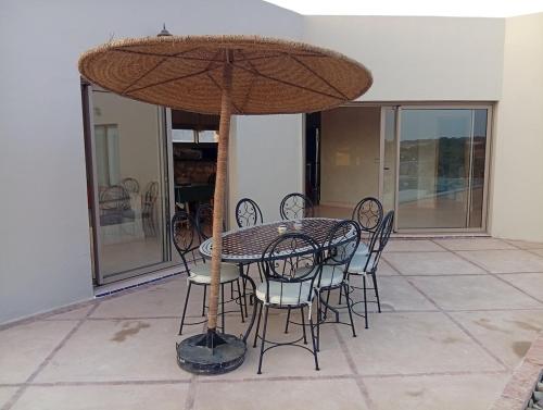 a table and chairs with a umbrella on a patio at Villa Khadija in Sidi Kaouki