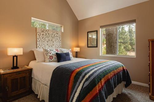 een slaapkamer met een groot bed en twee ramen bij Blissful Bay Cabin in Big Bear Lake