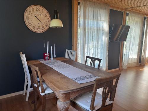 a dining room with a wooden table and a clock on the wall at Villa Bela in Högsby