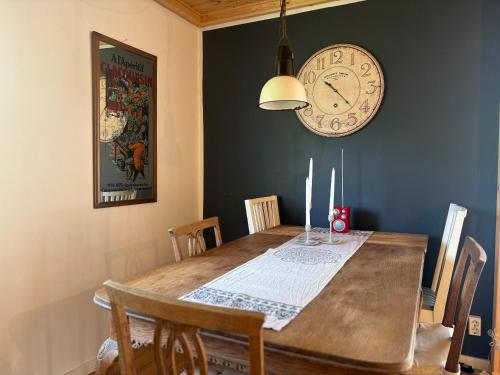 a dining room with a table and a clock on the wall at Villa Bela in Högsby