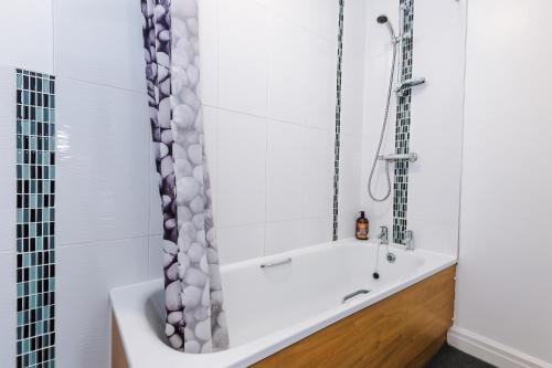 a white bath tub in a bathroom with a shower at Four BR House By Eason Stays Short Lets & Serviced Accommodation Chorley With Free Parking in Chorley