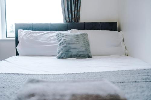 a bed with a blue pillow and white pillows at Four BR House By Eason Stays Short Lets & Serviced Accommodation Chorley With Free Parking in Chorley