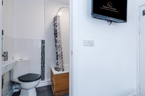 a bathroom with a toilet and a tv on the wall at Four BR House By Eason Stays Short Lets & Serviced Accommodation Chorley With Free Parking in Chorley