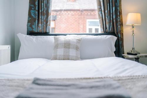 a bed with white sheets and pillows and a window at Four BR House By Eason Stays Short Lets & Serviced Accommodation Chorley With Free Parking in Chorley