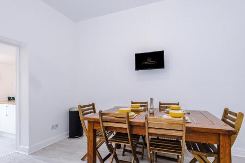a dining room table with wooden chairs and a television at Four BR House By Eason Stays Short Lets & Serviced Accommodation Chorley With Free Parking in Chorley
