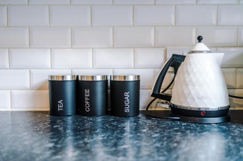 four coffee cups on a counter next to a blender at Four BR House By Eason Stays Short Lets & Serviced Accommodation Chorley With Free Parking in Chorley
