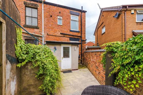 a courtyard with a white door and brick buildings at Four BR House By Eason Stays Short Lets & Serviced Accommodation Chorley With Free Parking in Chorley