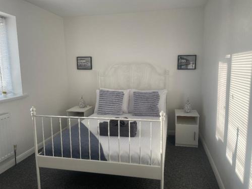 ein weißes Kinderbett in einem weißen Raum mit zwei Tischen in der Unterkunft 4 Bed Family & Work Ready Home in Ponders End