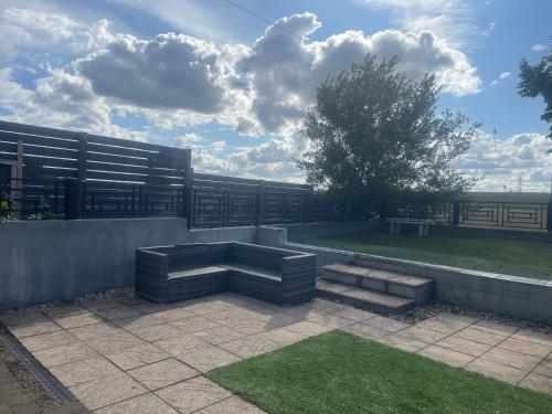 eine Terrasse mit einer Bank, einem Zaun und Gras in der Unterkunft 4 Bed Family & Work Ready Home in Ponders End