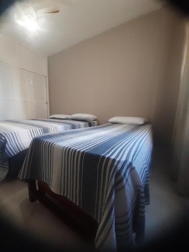 two beds in a room with blue and white sheets at castanheiras perto de tudo,com cadeiras e guarda sol in Guarapari