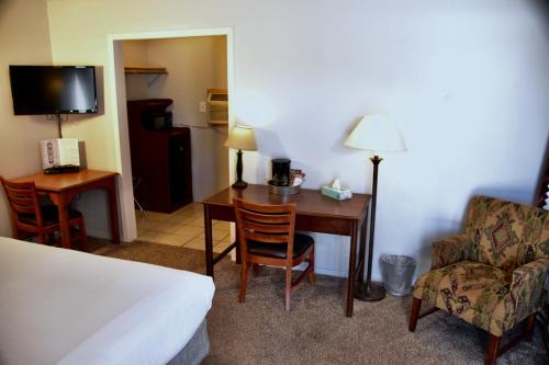 a hotel room with a desk and a chair and a bed at Yellowstone Holiday Motel in West Yellowstone