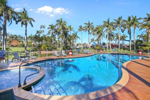 a large swimming pool with palm trees in a resort at Oaks Family Getaway - Resort, Beach in Golden Beach