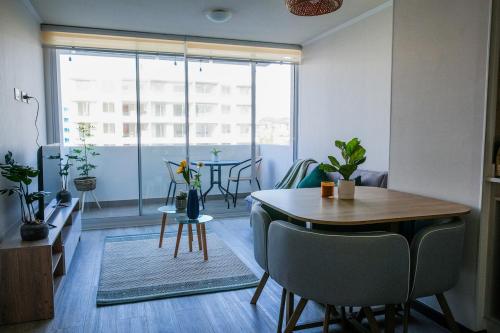un soggiorno con tavolo, sedie e una finestra di Departamento 2H1B La Serena Condominio Distrito Verde a La Serena