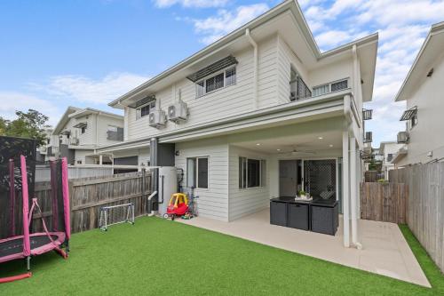 a white house with a yard with a playground at Carseldine Grove in Brisbane