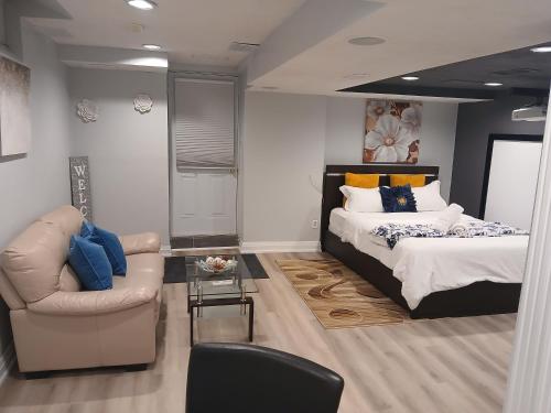 a bedroom with a bed and a couch and a chair at Furnished calm basement studio apartment in Mississauga