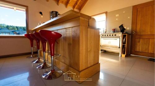 une cuisine avec comptoir et tabourets de bar rouge dans l'établissement Cabaña en Chapelco Golf San Martin de los Andes 2 Habitaciones, à San Martín de los Andes