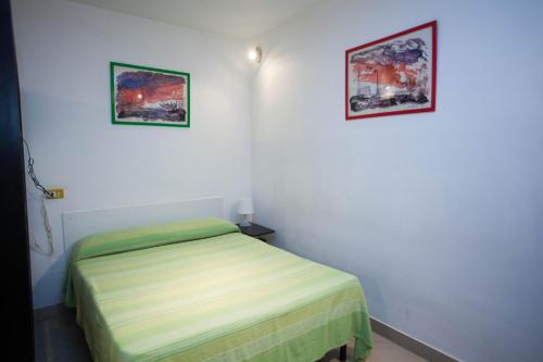 ナポリにあるSerra Casa Vacanza a Piazza del Plebiscitoのベッドルーム1室(ベッド1台付)が備わります。壁に2枚の写真が飾られています。