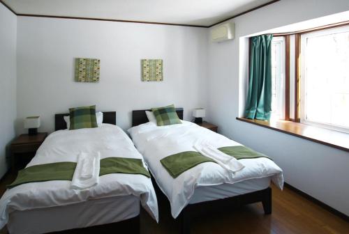 two beds in a white room with a window at Echo Villa the Spacious in Hakuba