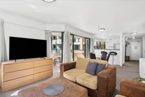 a living room with a flat screen tv and a couch at Stylish Braddon Retreat 2Bedroom Free Parking & Pool in Braddon