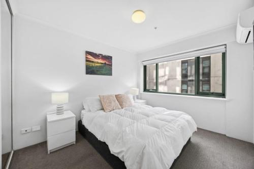 a white bedroom with a bed and a window at Stylish Braddon Retreat 2Bedroom Free Parking & Pool in Braddon