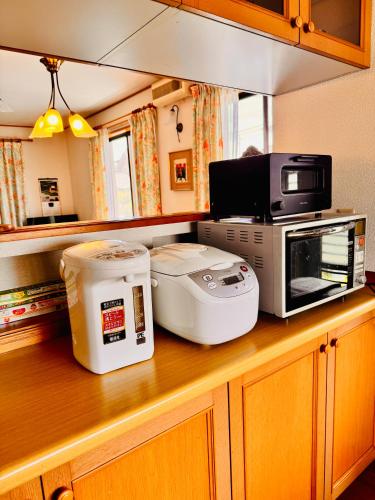 a kitchen counter with a microwave and appliances on it at 麗静亭 in Koga
