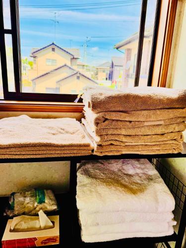 a pile of towels sitting in a room with a window at 麗静亭 in Koga