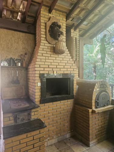 a brick fireplace in a room with a tv at Chalé in Itati