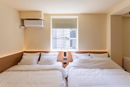 two beds in a room with a window at Yeobaek Hotel in Incheon