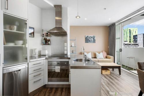 a kitchen with a sink and a couch in a room at Sunny and Central Wellington Apartment in Wellington
