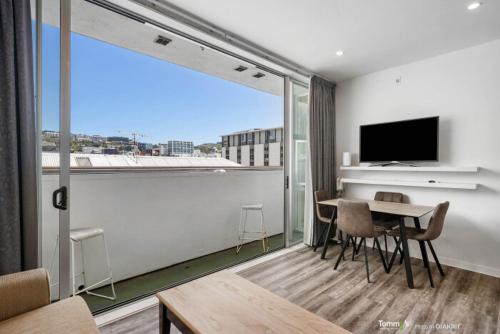 a living room with a table and a large window at Sunny and Central Wellington Apartment in Wellington