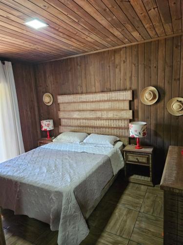 a bedroom with a bed and two tables with lamps at Chalé in Itati