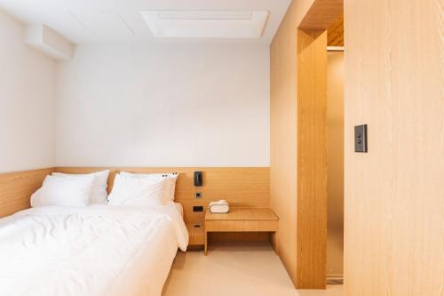 a small bedroom with a bed and a night stand at Yeobaek Hotel in Incheon
