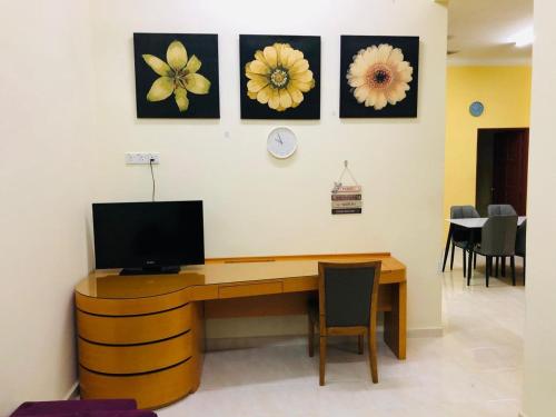 a room with a desk with a tv and flowers on the wall at Homestay Salam Marang Terengganu in Marang
