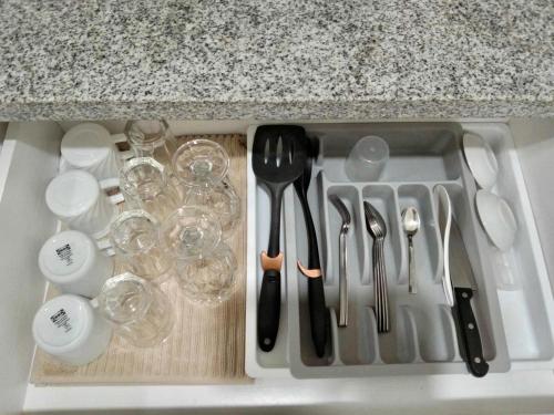 a kitchen sink with utensils and wine glasses and a counter at Nuvali - Free use of Massage Chair-Pool Access-Hot Shower in Calamba