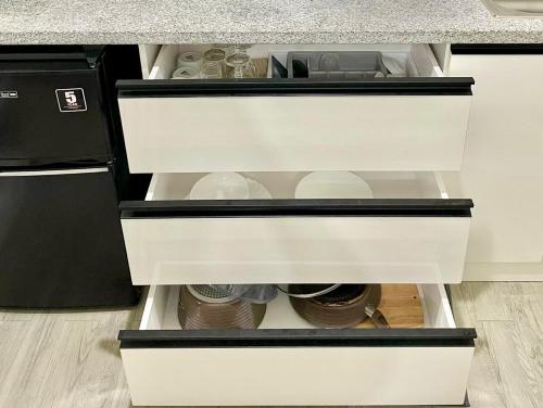 an open drawer in a kitchen with dishes at Nuvali - Free use of Massage Chair-Pool Access-Hot Shower in Calamba