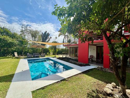 a swimming pool in a yard next to a house at La Casa Pina Pacifica near La Fortuna in San Ramón