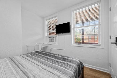 a white bedroom with a bed and a flat screen tv at Bloomfield Pittsburgh A Modern and Cozy Private Bedroom, Shared Bathroom, with Free Parking in Pittsburgh