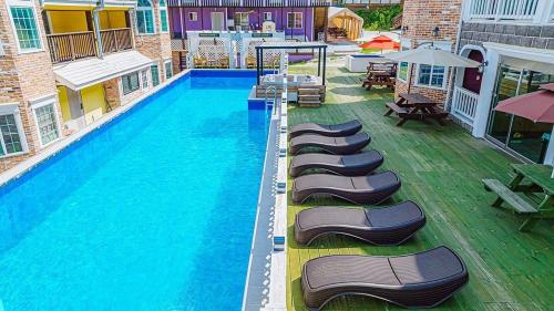 a large swimming pool with lounge chairs and umbrellas at Fun and Happy Pension Jungsun in Jeongseon