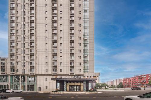 a tall building with a parking lot in front of it at 北京刘家窑地铁站万信至格酒店 in Beijing